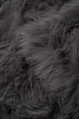 Detailed view of luxurious dark grey soft fluffy faux fur fabric material surface texture background