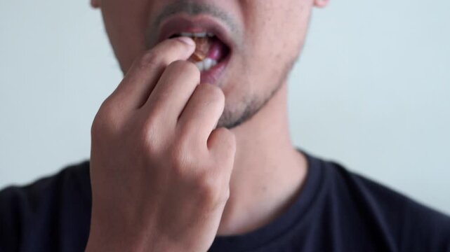Close-up of a bearded man eating a sweet date in warm, dramatic light, breaking fast in home