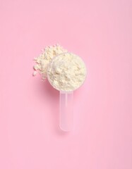 Protein powder scoop with supplement on pink background