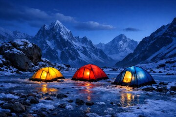 View of illuminated mountaineering tents standing on a wet ice flat in the blue hour twilight at base camp with the big rocks and high snow mountain in the background.