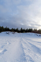 Obraz premium Vehicle tracks on snowy dune path