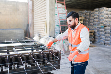 Industrial worker fabricating steel rebar cage for construction, building structure reinforcement and industrial processes