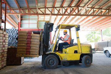 Forklift driver moving cement bags on pallet in warehouse, managing construction supply logistics and industrial inventory © AntonioDiaz
