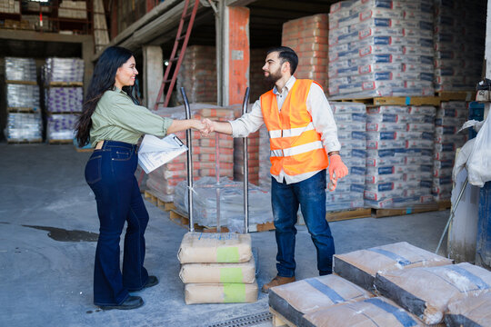 Handshake between business professionals in a construction supply warehouse, completing a b2b deal for building materials