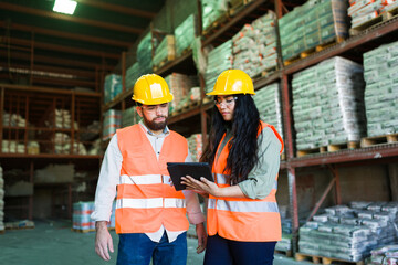 Warehouse workers collaborating on inventory management using a digital tablet in construction supply store