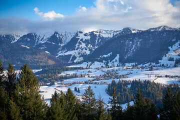 Winter landscape at the foot of the Nagelfluhkette with the snow-covered Hochgrat peak above Steibis near Oberstaufen in the Allg&auml;u region of Bavaria, Germany, under soft afternoon light.