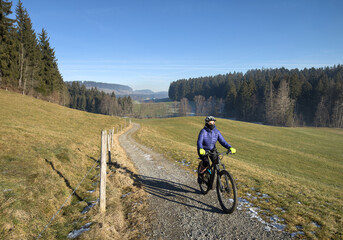 Obraz premium Woman cycling with her electric mountain bike on a cold and icy winterday in t5he Allgaeu Alps, Bavaria, Germany 