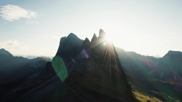 Dramatic sunrise over Seceda mountain peaks with bright sun flare