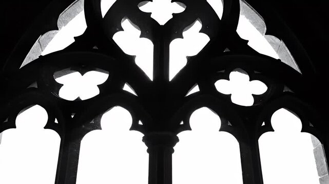 Black and white Gothic window with intricate tracery, silhouetted against a bright background