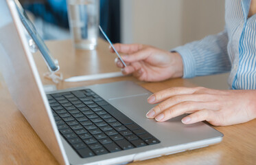 Fototapeta premium Woman holding credit card and using laptop for online payment. E commerce, digital banking, fintech transaction, cybersecurity and secure internet shopping concept in modern business lifestyle