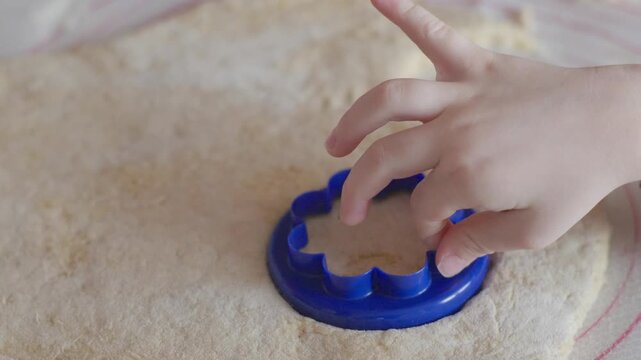 Little boy hand helping with cutting dough for European made healthy doughnut