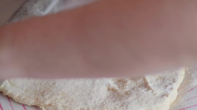 Hand dusting dough with flour and rolling it with pin for European made doughnut