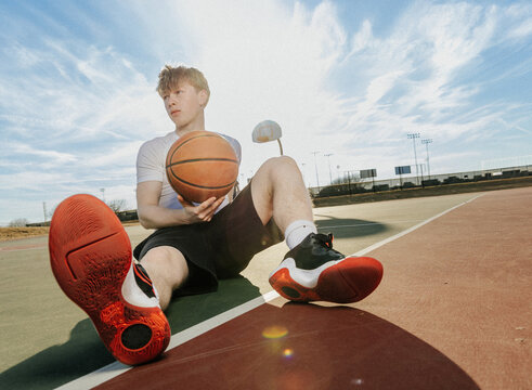 Young Man Holding a Basketball on an Outdoor Court