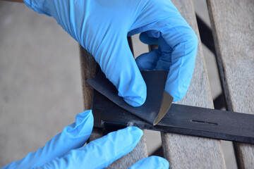 The mechanic is using sandpaper to sand the workpiece.