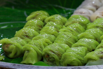 Rows of Steamed Thai Rice Skin Dumplings (Khao Kriap Pak Mor) with Vibrant Green Skins Arranged on a Fresh Banana Leaf. © Leiter1940s