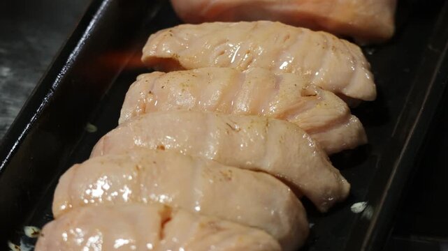 Several Aburi Salmon Nigiri Sushi Pieces Being Seared with a Kitchen Torch Flame on a Long Black Serving Plate.