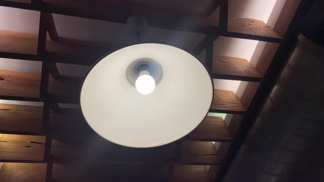 Modern industrial pendant light fixture illuminating rustic wooden ceiling beams