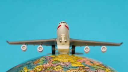Airplane on a globe against a blue background. Close-up