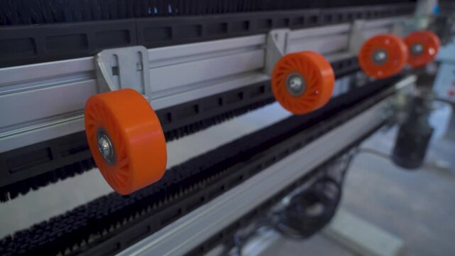 Industrial conveyor belt system with orange wheels moving