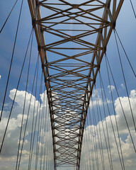 Fototapeta premium Symmetrical steel bridge structure perspective with geometric lines against blue sky background