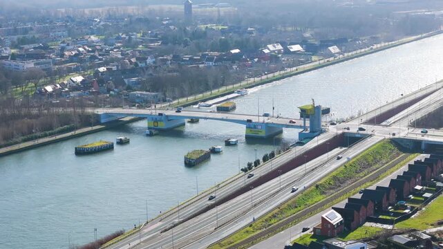 elevated zelzatebrug bascule bridge spanning shimmering ghent&ndash;terneuzen canal vehicles crossing water while multi lane highway runs parallel bank to reveals drone shot belgium 