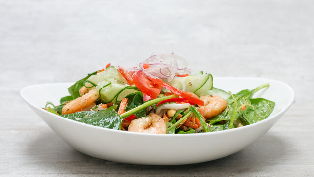 Close up of a prawn (shrimp) salad with peppers, tomatoes, cucumber on a white plate