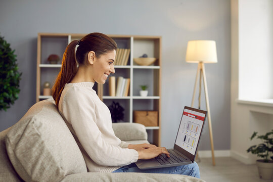 Woman freelancer working on laptop at home. She reviews finance data, manages budgeting and savings, and handles accounting in a cozy living room. Ideal for remote work and finance visuals.