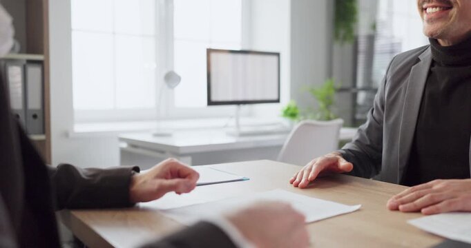 Business client office meeting with contract signing. Hands review paperwork and documents, finalizing an agreement at a modern desk in a bright corporate space. Concept shows trust in business.