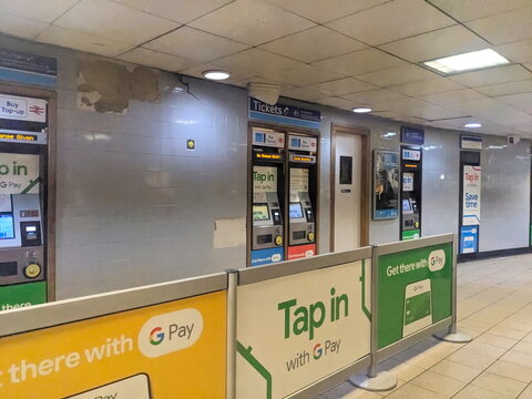 Ticket machines with contactless G Pay payment options at a London transport station concourse