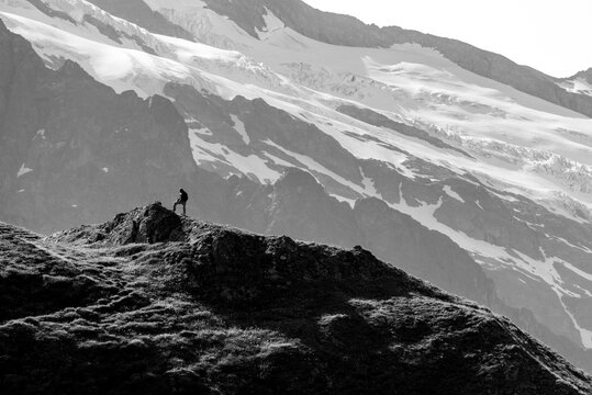A hiker reached a small mountain summit and viewing towards a muh higer summit