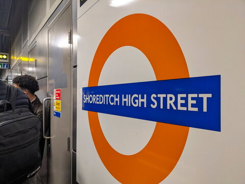 Close-up of the iconic Shoreditch High Street London Overground station roundel sign indoors