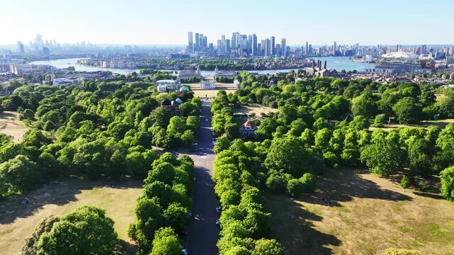Aerial drone cinematic video over iconic park of Greenwich Royal Observatory, University and Canary Wharf skyscraper complex at the background, London, United Kingdom