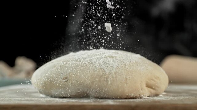 The dough on the kitchen table with falling flour . Filmed on a high-speed cinema camera at 1000 fps