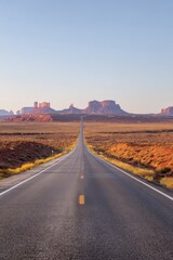 Scenic desert highway stretching towards distant mesas at sunrise