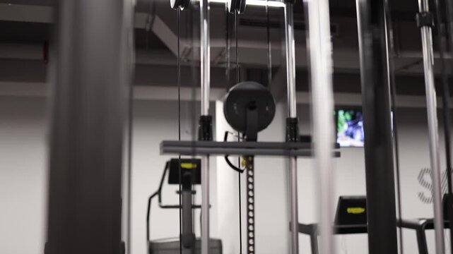 Young athletic woman performs lat pulldown on cable machine strengthening back and shoulders with controlled movement during intense gym workout session