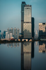 Obraz premium Bangkok skyline panorama with reflection in calm water, Modern cityscape of Thailand capital mirrored on swimming pool or lake surface under cloudy sky