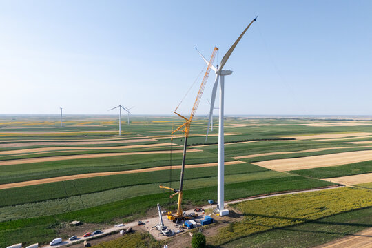 Wind turbine installation using a large construction crane. The assembly process of the turbine tower and rotor blades. Aerial view