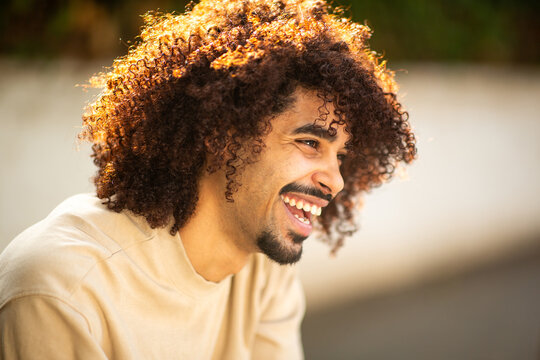 Afro latino man laughing under warm sunlight with natural curly hair