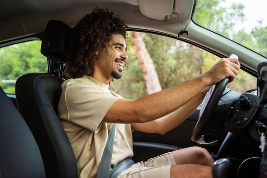 Smiling afro latino man driving car with seatbelt and enjoying the ride