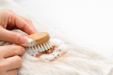 Cleaning a Fabric With a Brush and Soap to Remove Stains While Holding the Brush Firmly in One Hand