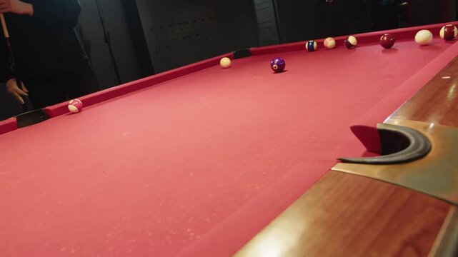 Competitive game with forceful precise shot on vibrant red felt billiard table. Caucasian calm adult man lines up powerful break shot during leisure time. The ball successfully falls in the pocket