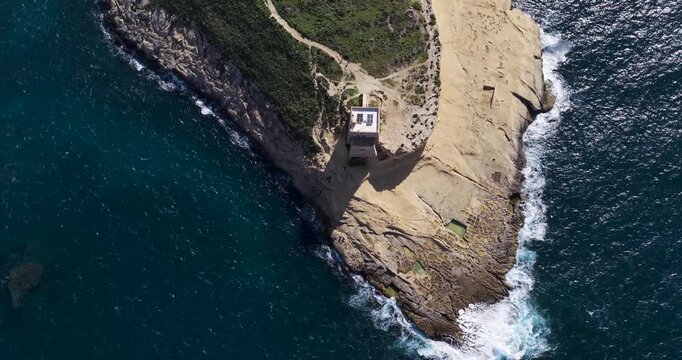Aerial view of Xlendi Tower standing proud against the backdrop of the azure sea and rugged coastline, creating a stunning contrast, Xlendi, Munxar, Malta.