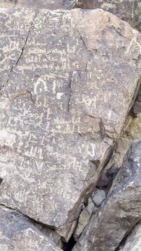 A detailed look at historical Kufic inscriptions carved into ancient stone. This footage showcases early Islamic calligraphy and archaeological rock art found in the rugged mountains in Medina.