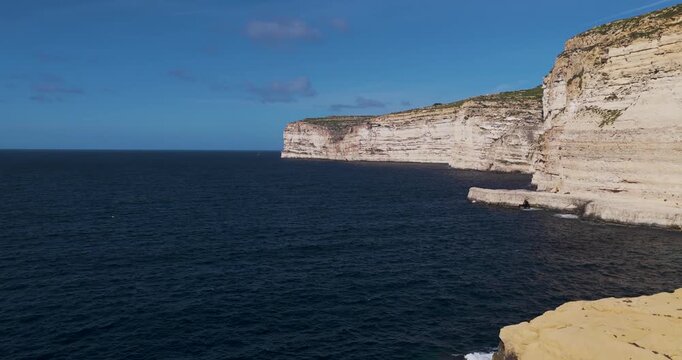 Aerial view of steep cliffs overlooking the deep blue sea, contrasting textures and tones of the landscape, Xlendi, Munxar, Malta.