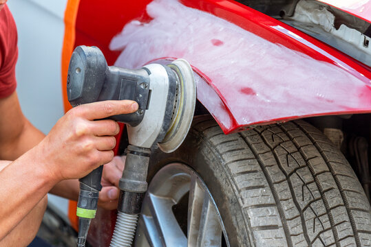 Repairing car body by puttying close up work after the accident by working sanding primer before painting. , The mechanic repair the car.