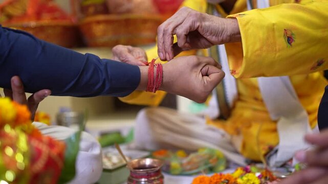 Hindu Priest Tying Sacred Red Kalava Thread on Devotee Wrist