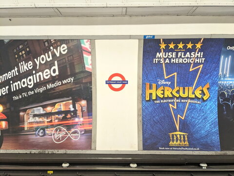 Vibrant commercial advertisements along the tracks at Tottenham Court Road Underground station, London
