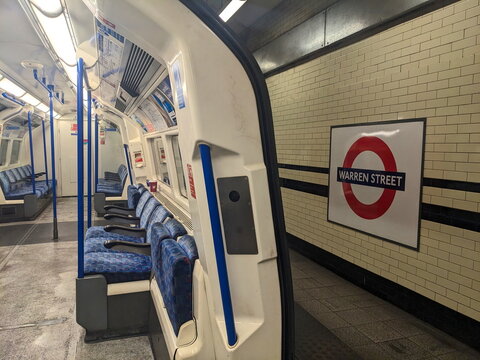 View of an empty London Underground tube train with blue moquette seats at Warren Street station