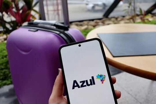 Azul Linhas A&eacute;reas app (Azul Brazilian Airlines) with a suitcase in the background at the airport.