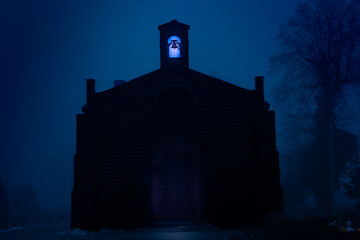 Cmentarz komunalny w mieście Żagań w Polsce. Cmentarny dom przedpogrzebowy pogrążony w ciemnościach i unoszącej się nad ziemią mgłą. © boguslavus